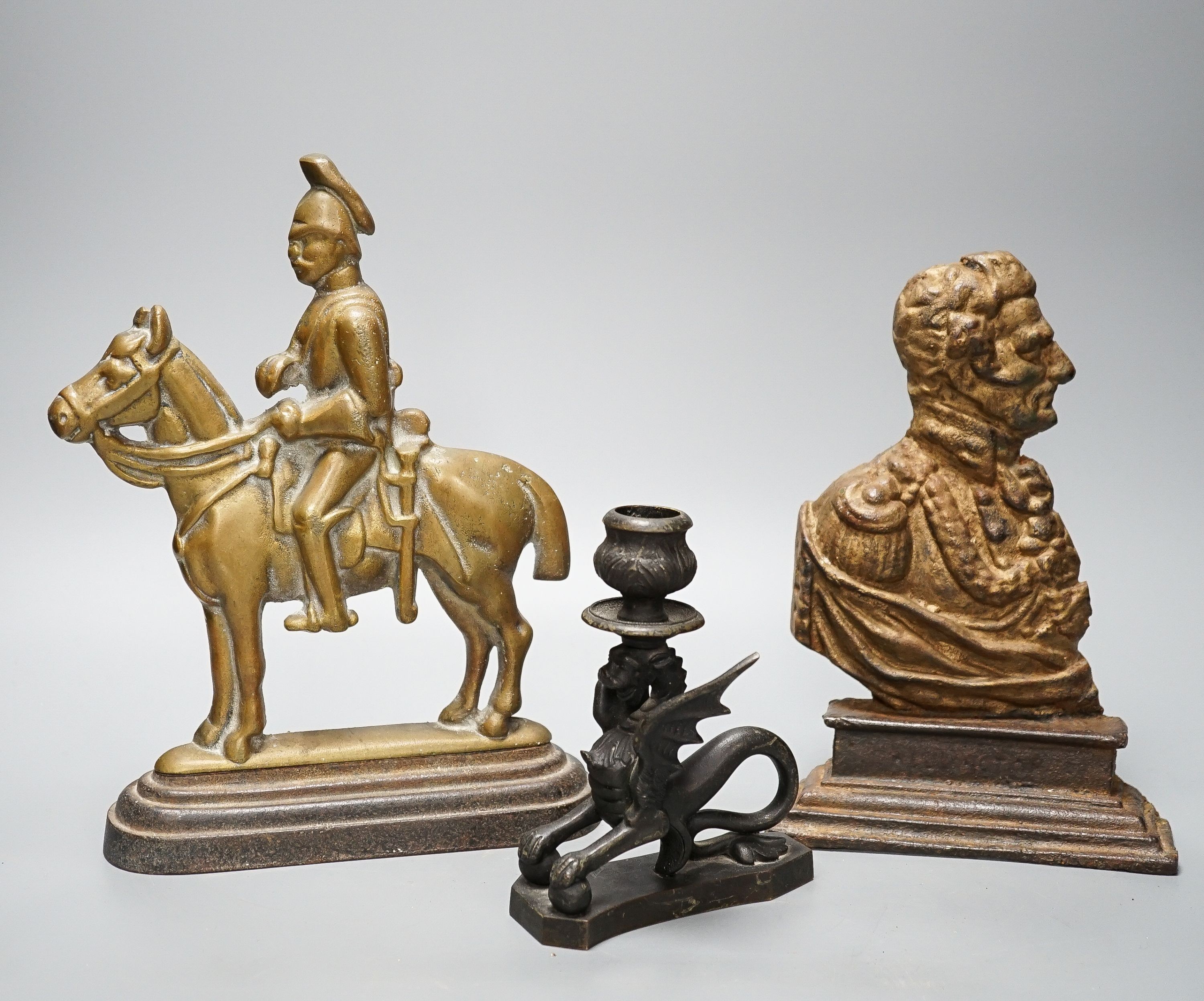 Two brass and cast iron military doorstops and a brass chamberstick 26cm